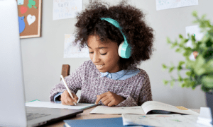 young kid writing in front of a computer